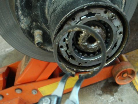 1996 Ford Bronco - Removing a retaining ring from a vehicle's hub assembly with pliers.