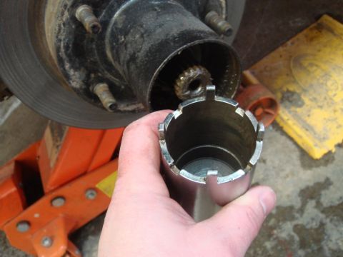 1996 Ford Bronco - A socket wrench tool is held up to a vehicle's wheel hub assembly, likely for maintenance or repair.