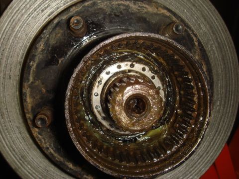 1996 Ford Bronco - Greasy wheel hub assembly and brake rotor with visible internal gears and splines.