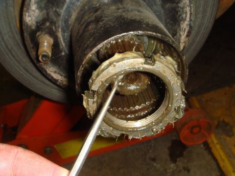 1996 Ford Bronco - A tool is used to adjust the nut on a heavily greased wheel bearing assembly.