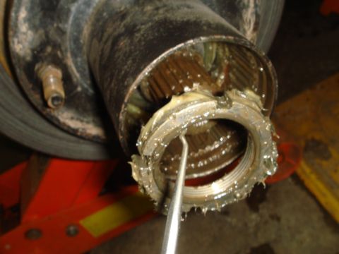 1996 Ford Bronco - Close-up of a greased wheel hub assembly with a tool being used to remove a nut.
