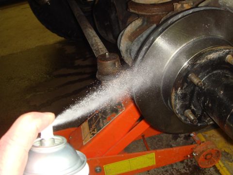 1996 Ford Bronco - Spraying brake rotor with cleaner during maintenance.