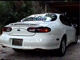 1997 Ford Taurus - Rear view of a white 1997 Ford Taurus, showing its distinctive taillights and body style.