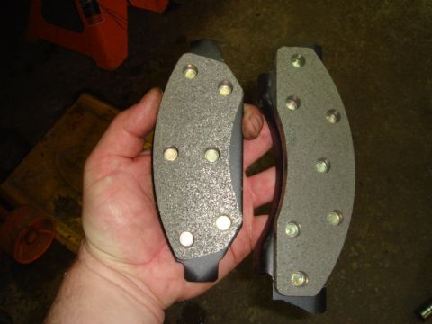 1996 Ford Bronco - Two new brake pads are held in a hand, ready for installation.