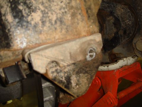 1996 Ford Bronco - Close-up of a heavily corroded vehicle suspension part supported by an orange jack stand.