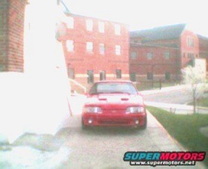 1998 Ford Crown Victoria - A red Ford Mustang is parked in front of a brick building.