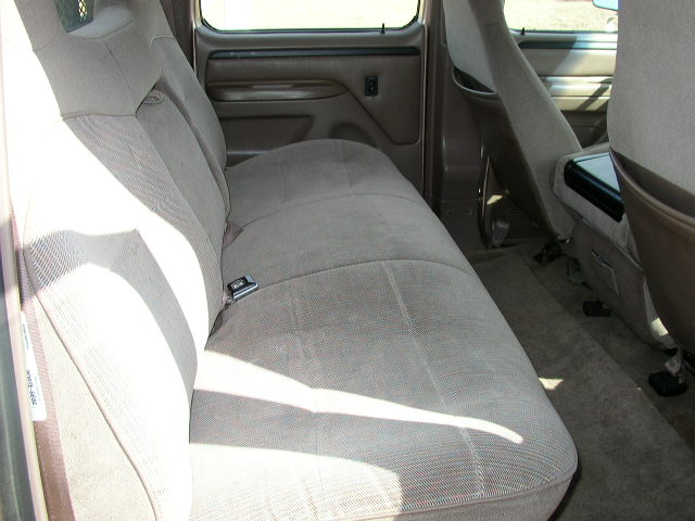 Tan cloth rear bench seat in a Ford crew cab truck viewed through the open rear door