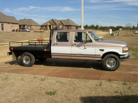 1995 Ford Bronco - This Ford F-350 truck has a flatbed and a dual cab, seen from the side.