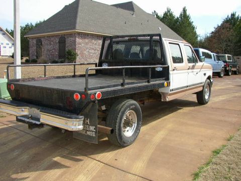 1995 Ford Bronco - This 1995 Ford F-350 flatbed truck is parked in a driveway with other vehicles visible.