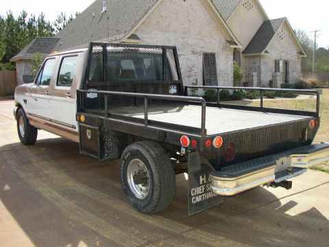 1995 Ford Bronco - This Ford F-350 truck features a flatbed and a headache rack, seen from a rear angle.