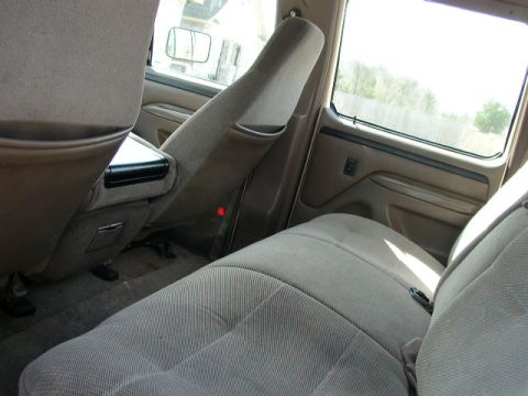 1995 Ford Bronco - The interior of a truck, showing the rear seating area and center console, with a view out the window.