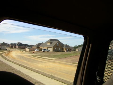 1995 Ford Bronco - View from inside a vehicle shows a suburban street with two trucks and a car.