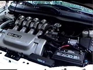 1997 Ford Taurus - The engine bay of a 1997 Ford Taurus SHO is visible, with the V8 engine and intake manifold prominently displayed.