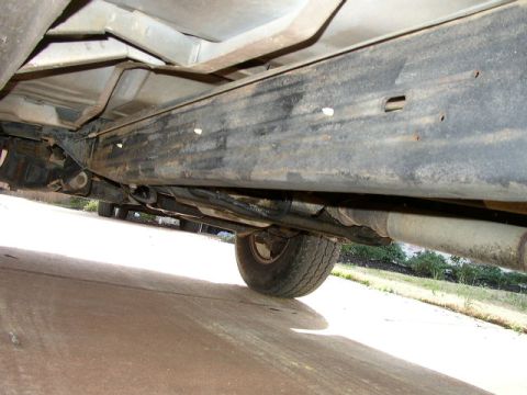 1995 Ford Bronco - The underside of a vehicle shows its frame, suspension components, and exhaust system.