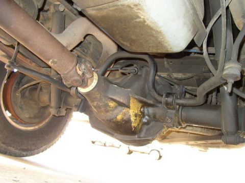 1995 Ford Bronco - Underside view of a vehicle's rear axle, driveshaft, and suspension components, with a faint outline of another vehicle visible below.