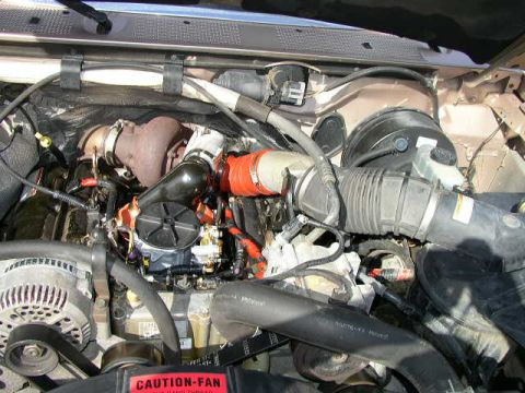1995 Ford Bronco - Close-up view of the engine bay, highlighting the turbocharger and various hoses. A "CAUTION-FAN" warning label is visible.
