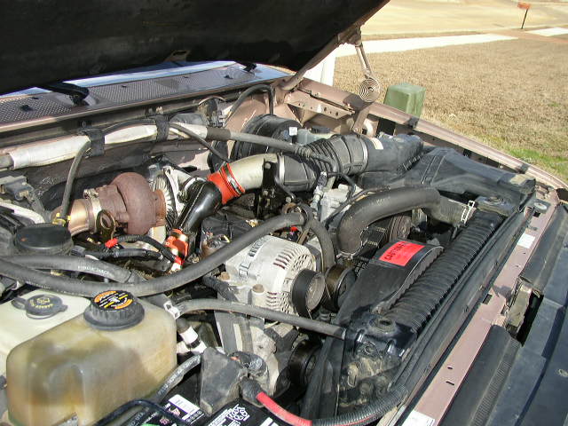Engine bay showing a turbocharger, alternator, and radiator. Some hoses and belts are visible