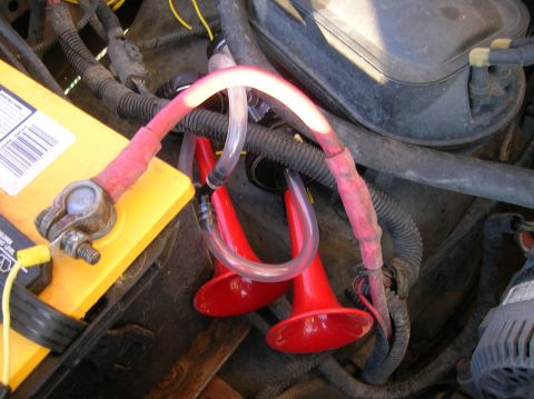 1996 Ford Bronco - Aftermarket air horns are installed near the vehicle's battery and engine components.