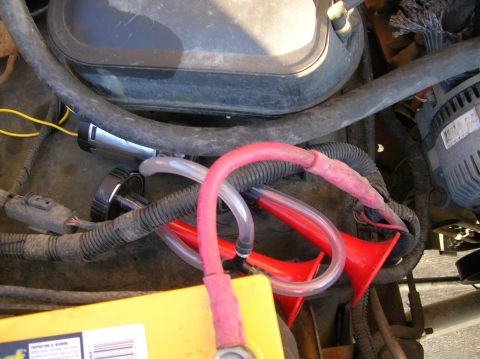 1996 Ford Bronco - Close-up view of an aftermarket air horn system installed in a vehicle's engine bay.