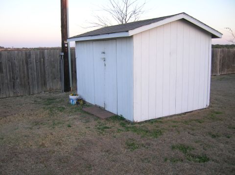 1996 Ford Bronco - Exterior view of a white storage shed next to a wooden fence and utility pole.