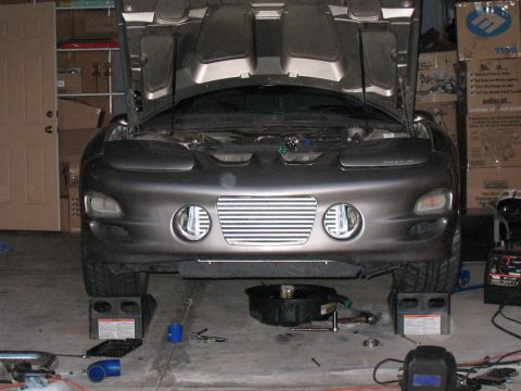 2001 Pontiac Trans Am - The front of a gray 2001 Pontiac Trans Am is shown with its hood open, raised on jack stands in a garage setting.