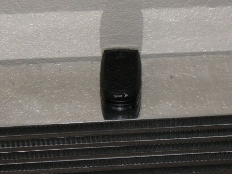 2001 Pontiac Trans Am - A black Sprint cell phone rests on a metal grate.