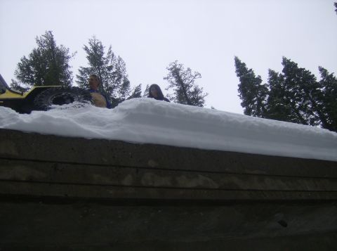 1986 Ford Bronco - Two individuals are seen atop a snowdrift next to a yellow vehicle, suggesting a winter scene.