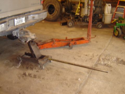 1992 Ford Bronco - A vehicle is supported by jacks in a workshop environment with various tools and equipment visible.