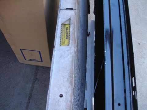 1992 Ford F-350 - A radiator part is shown with a caution sticker and a cardboard box in the background.