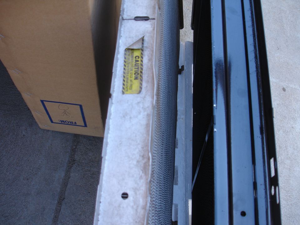 Radiator with a yellow 'CAUTION' sticker and a cardboard box with 'FROM:' label