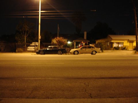 1991 Ford Taurus - Two sedans are parked side-by-side on a street at night, illuminated by streetlights.