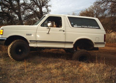 1987 Ford Bronco - White 1987 Ford Bronco with lifted suspension driving off-road.