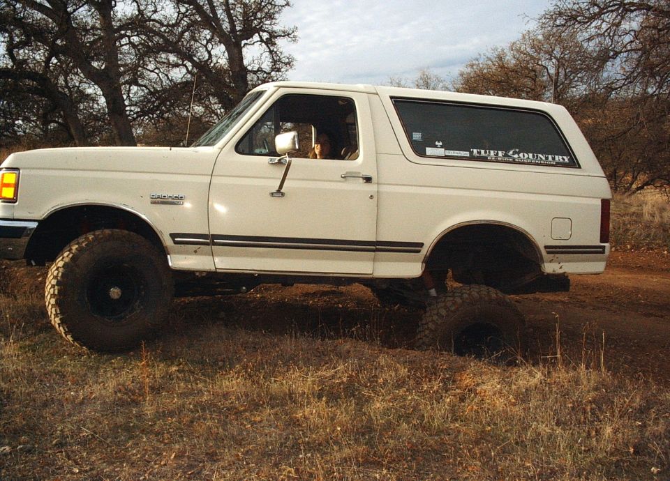 White 1987 Ford Bronco with lifted suspension on a dirt road