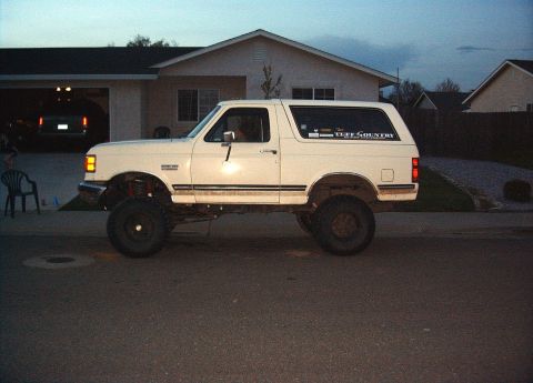 1987 Ford Bronco - This lifted 1987 Ford Bronco features a prominent 'Tuff Country' decal on its rear window, indicating aftermarket suspension modifications.