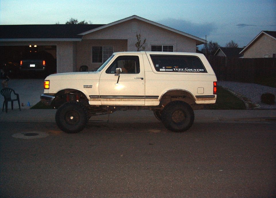 White 1987 Ford Bronco with lifted suspension and 'Tuff Country' sticker on rear window