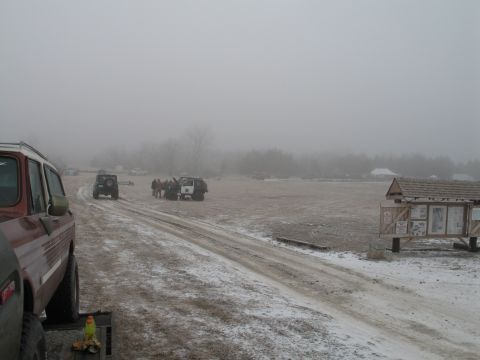 1995 Ford Bronco - Multiple vehicles are parked in a field on a foggy day with a light dusting of snow.