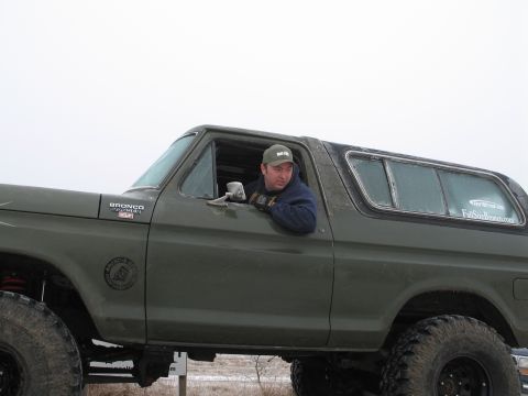 1995 Ford Bronco - Man in a lifted green Ford Bronco, likely from the late 1970s.
