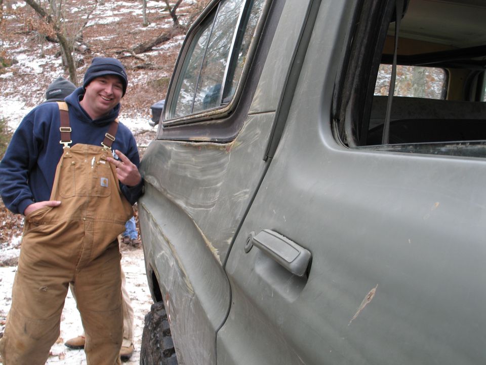 Green SUV with a dented fender and a worn door handle, seen from the side