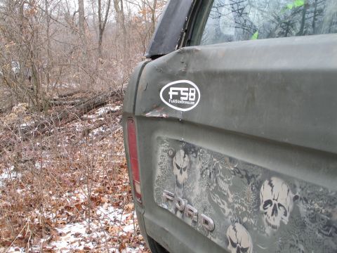 1995 Ford Bronco - The rear of a green Ford truck features skull graphics and an FSB sticker, with a wooded background.