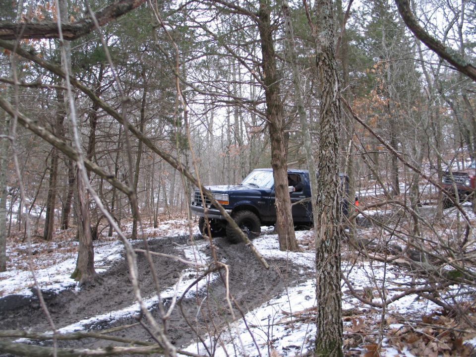 Dark blue SUV on muddy trail with snow, 3/4 front view