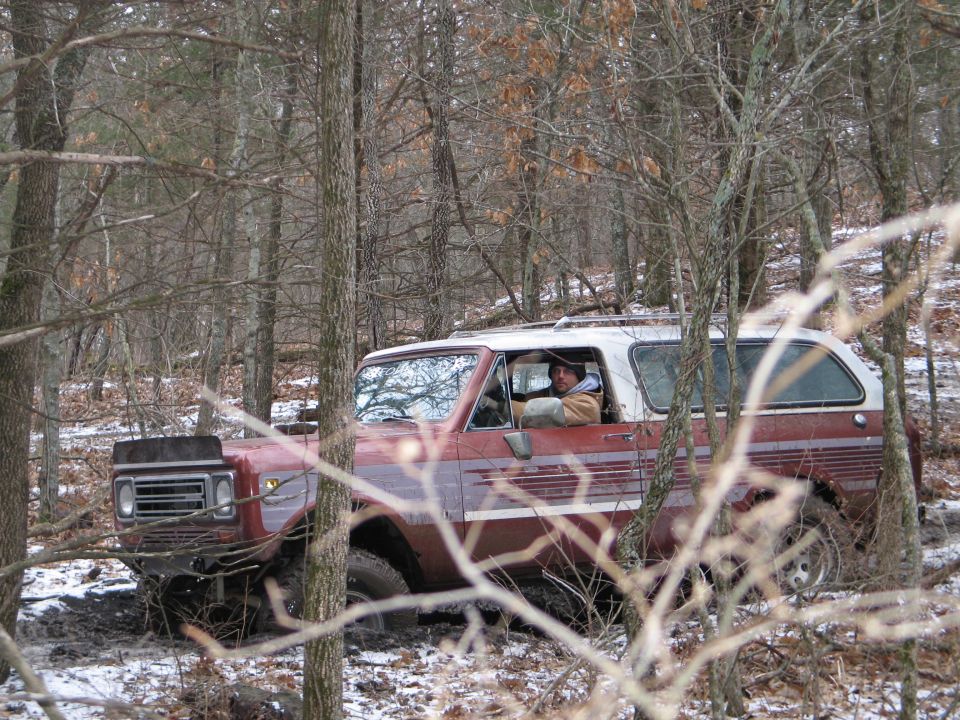 Red and white SUV stuck in muddy woods