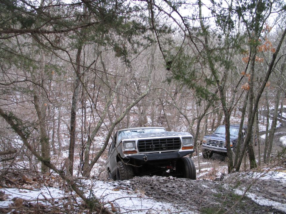 Gray Ford Bronco with aftermarket bumper driving off-road in snow and mud