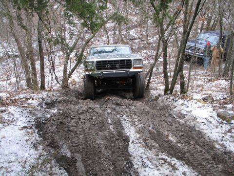 1995 Ford Bronco - A 1979 Ford F-Series truck navigates a challenging muddy and snowy trail, with another vehicle visible in the background.