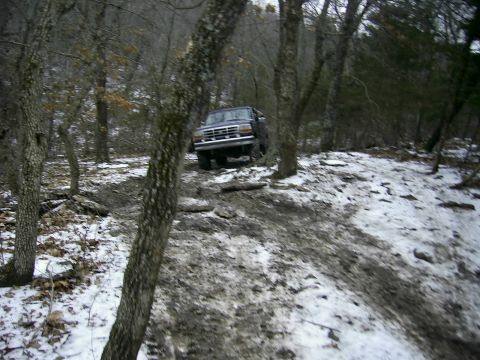 1978 Ford Bronco - A Ford Bronco navigates a challenging off-road path covered in mud and snow.