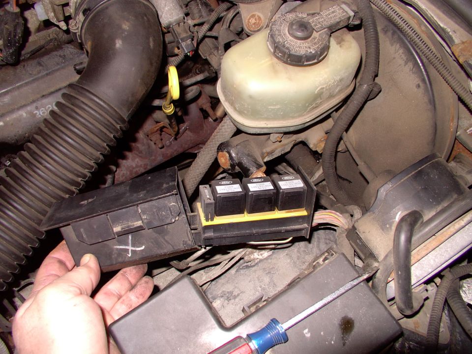 Ford under-hood relay and fuse box with cover open, brake reservoir nearby