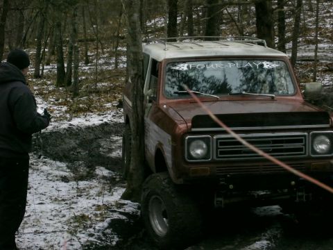 1978 Ford Bronco - A brown International Harvester Scout II with a white roof is stuck in a muddy, wooded area.