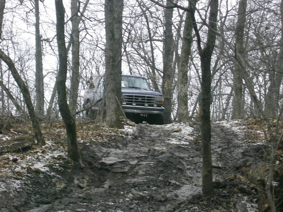 Dark SUV on a muddy, wooded trail