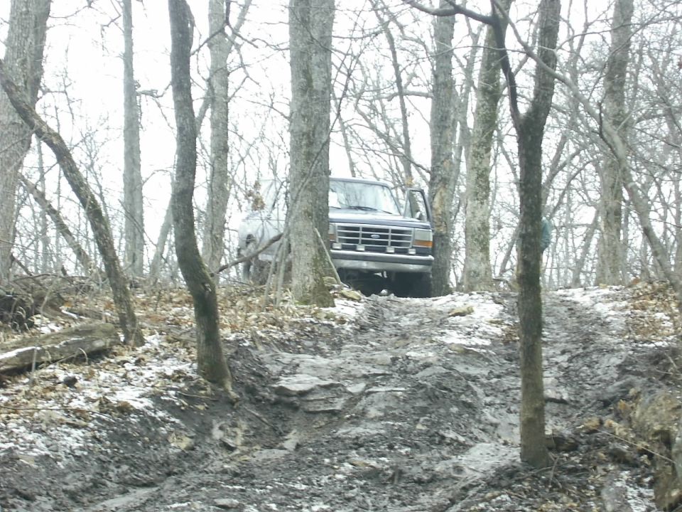 Dark gray Ford Bronco on a muddy, wooded trail