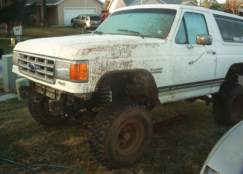 White 1987 Ford Bronco with mud splatter and lifted suspension