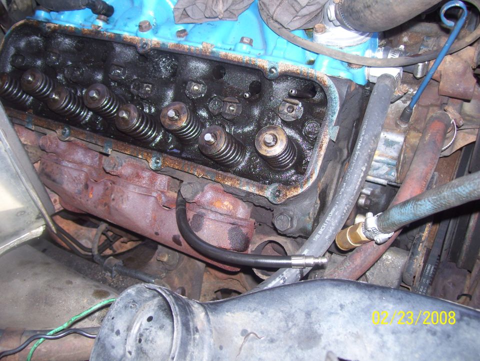 Close-up of engine valve train with visible rust and oil buildup. Date stamp reads 02/23/2008